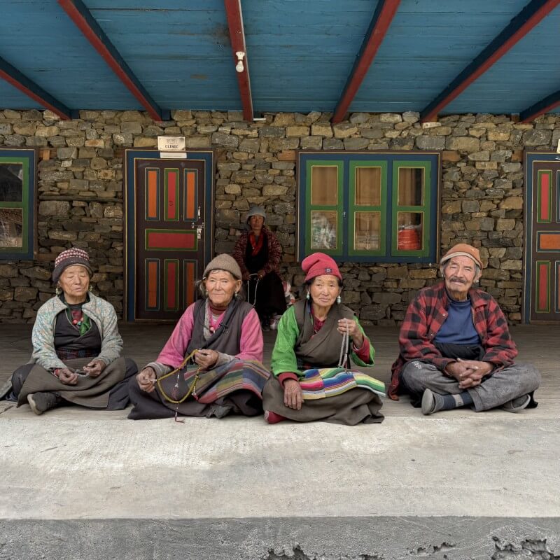 Vier Bewohnerinnen sitzen vor einem Gebäude der Serang Gompa